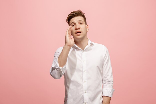 Isolato su rosa giovane uomo casual che grida in studio