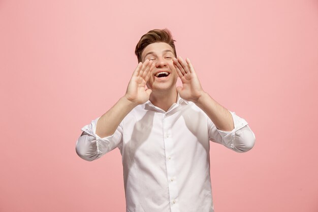 Isolato sul giovane uomo casuale rosa che grida allo studio