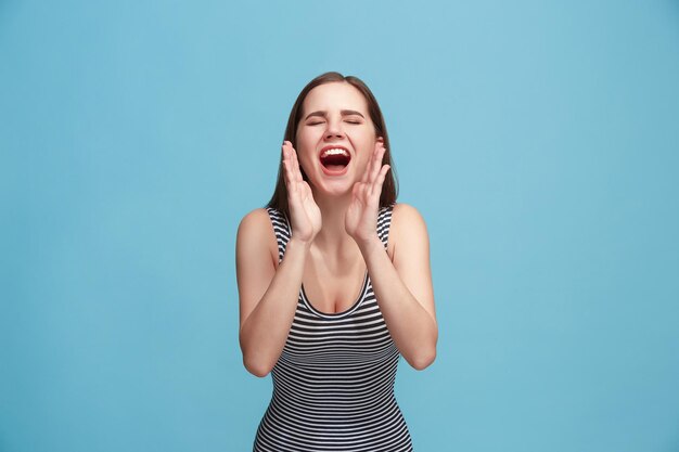 Isolato sulla giovane donna casuale blu che grida allo studio