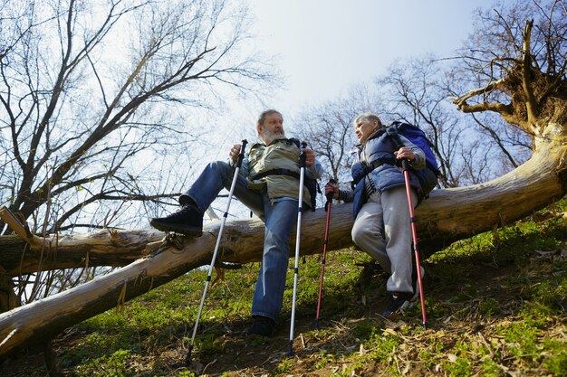 Ispirazione per vivere. Coppia di famiglia invecchiato dell'uomo e della donna in abito turistico che cammina al prato verde vicino agli alberi in una giornata di sole. Concetto di turismo, stile di vita sano, relax e solidarietà.