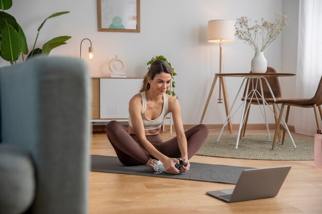 Istruttore di fitness femminile che utilizza il computer portatile per insegnare una lezione da casa