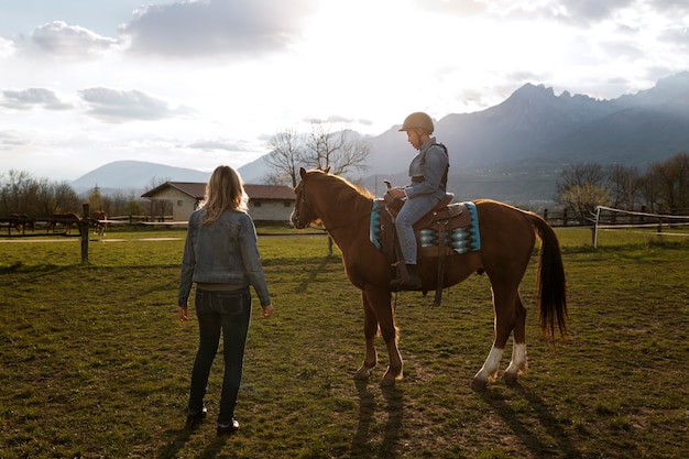 Istruttore equestre femminile che insegna al bambino come andare a cavallo