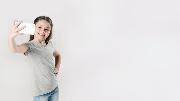 Junior minore che prende selfie sul telefono in studio