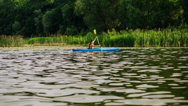 Kayak maschile con pagaia sulla superficie dell&#39;ondulazione dell&#39;acqua