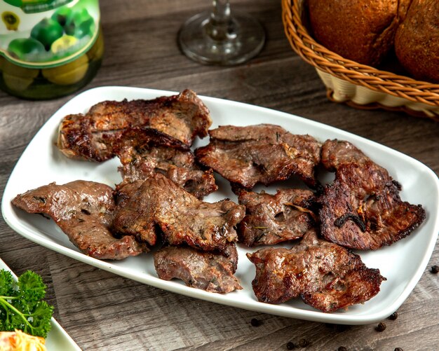 Kebab del basturma della carne di vista laterale su un piatto con pane