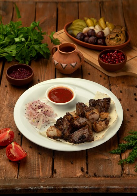 Kebab di agnello servito con cipolle e sumac, salsa di pomodoro ed erbe aromatiche