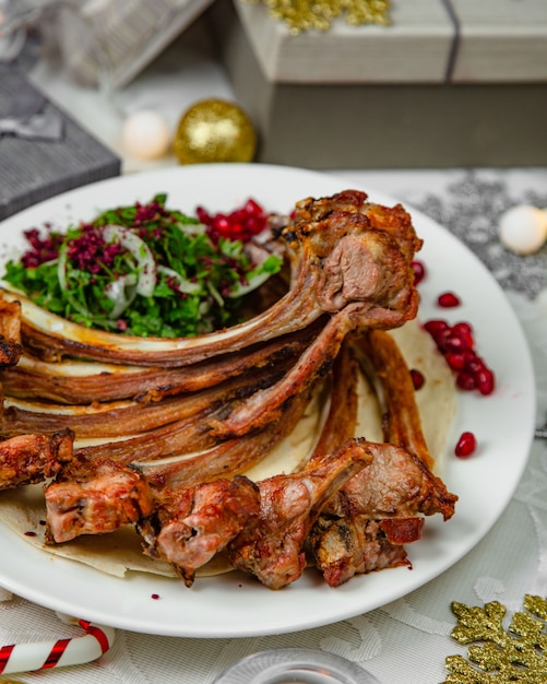 Kebab di agnello servito con erbe di cipolla e insalata di melograno