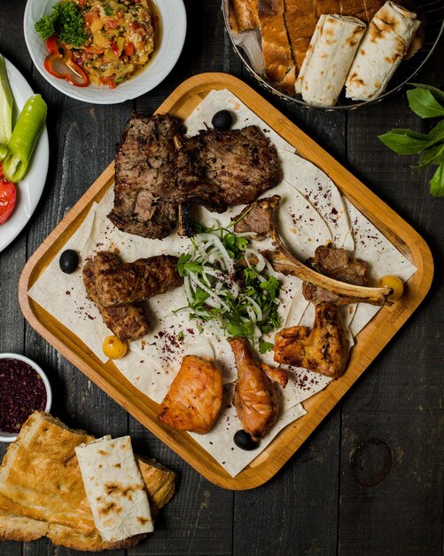 Kebab di carne caucasica con insalata di cipolle alle erbe all'interno del piatto di legno.