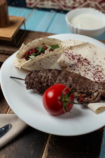 Kebab di carne in lavash con pomodoro, erbe e spezie.