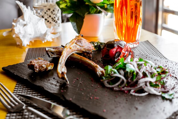 Kebab di costolette di agnello vista laterale con pomodoro grigliato e cipolle alle erbe