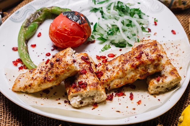 Kebab di lula del pollo di vista frontale sul pane della pita con il pomodoro e pepe grigliato con le cipolle e le erbe