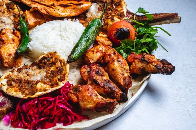 Kebab di pollo di vista laterale con il cavolo ed il riso marinati pomodoro caldo caldo del peperone verde sulla pita