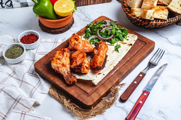 Kebab di pollo di vista laterale sul pane della pita con le erbe e le cipolle su una lavagna