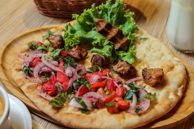 Kebab di pollo vista laterale con pomodoro cipolla ed erbe sul pane tandoor