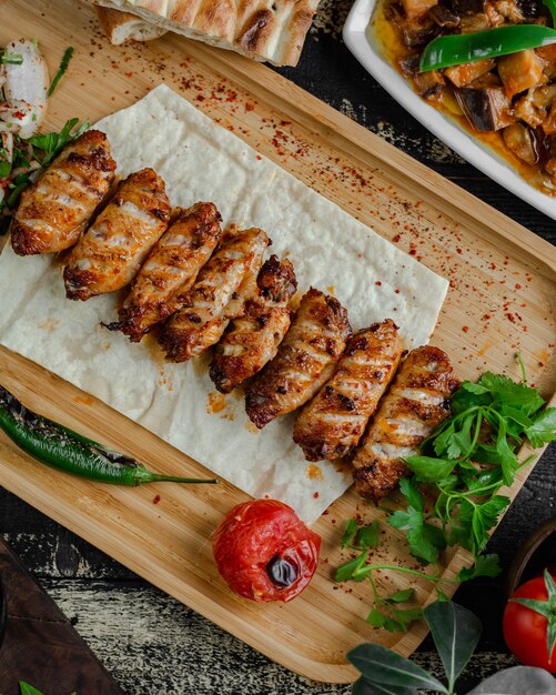 Kebab nazionale del barbecue della carne nel lavash con prezzemolo e il pomodoro grigliato.