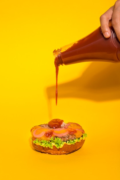 Ketchup che versa sul panino gustoso hamburger