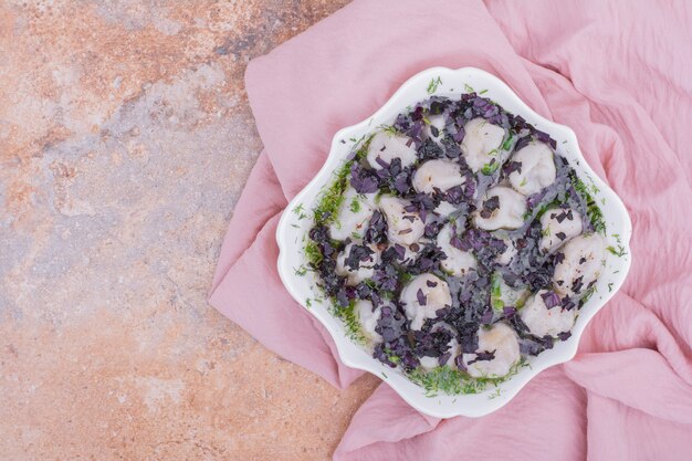 Khinkali caucasico crudo in una ciotola con erbe tritate