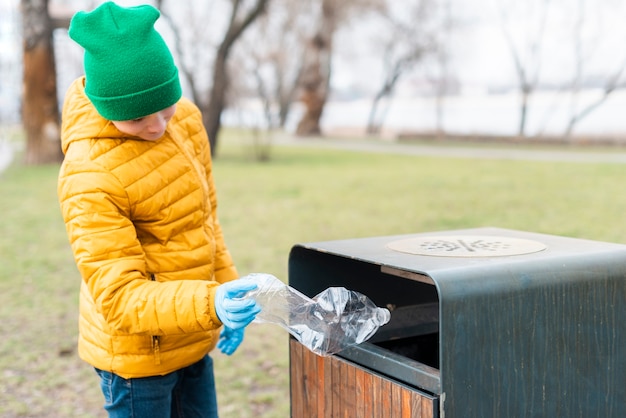 Kid gettando la bottiglia di plastica nel cestino