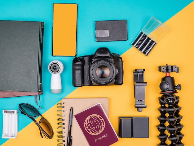 Kit blogger viaggiatore per le vacanze estive. Vista dall'alto. Disposizione piatta. Fotocamera con accessori accanto a occhiali da sole, libri, smartphone, quaderno di carta e passaporto