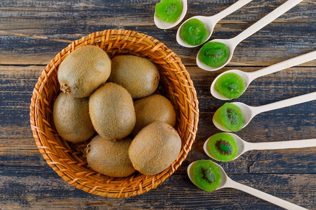 Kiwi con fette essiccate in un cesto su sfondo di legno, piatto laici.