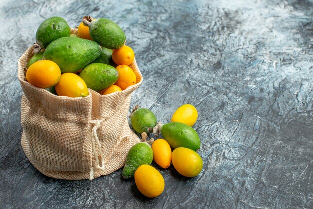 Kumquat freschi dentro e fuori di una piccola borsa bianca