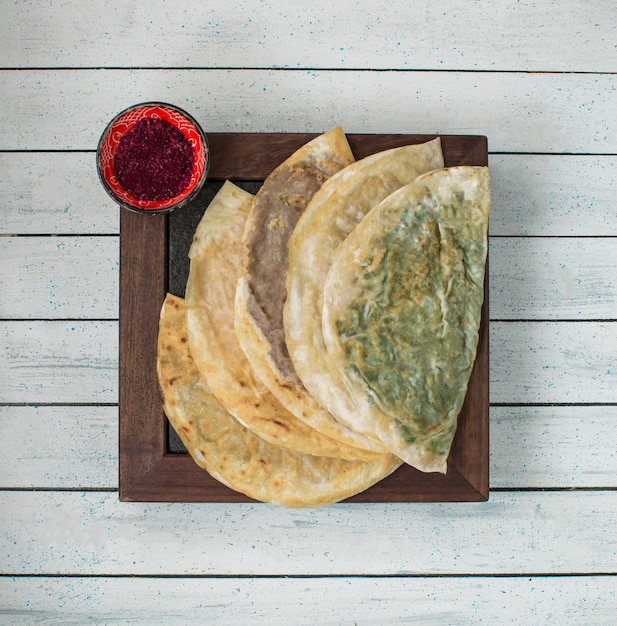 Kutab caucasico nel lavash con paprica su un bordo di legno.