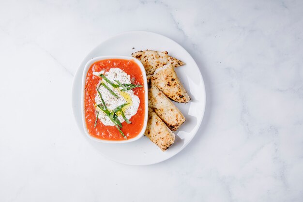 Kutab caucasico servito con salsa di pomodoro e crema di formaggio in cima.