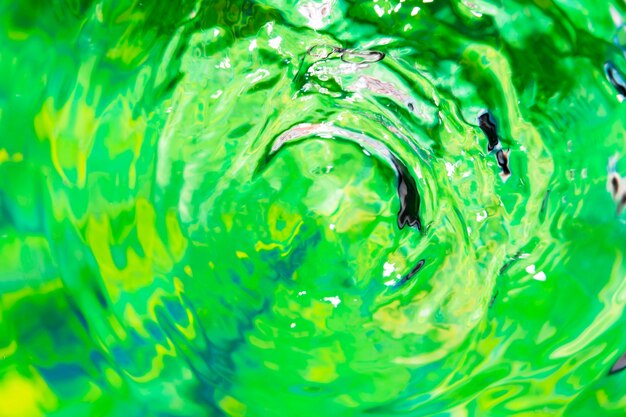 L'acqua del primo piano suona su una superficie verde dello stagno