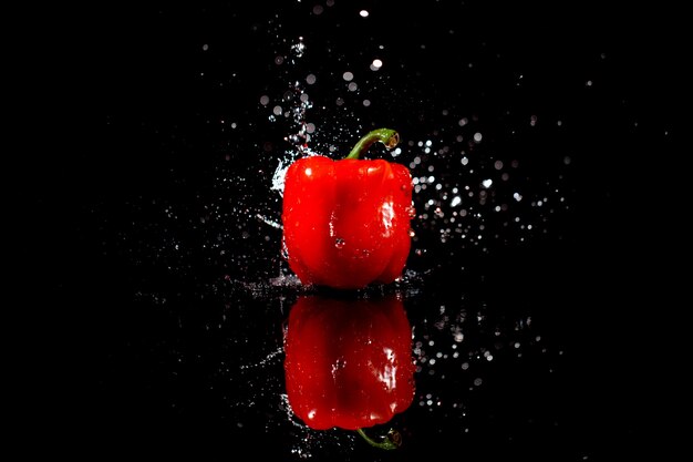 L&#39;acqua scintillante cade sul pepe rosso delizioso che si trova sul tavolo nero
