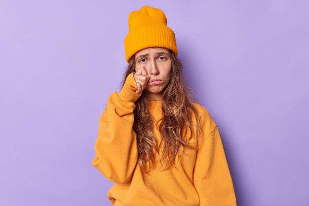 L'adolescente affronta problemi singhiozza e asciuga le lacrime si alza molto turbato indossa un maglione arancione casual e il cappello esprime emozioni negative isolate sul viola si sente il cuore spezzato. Ansia da stress