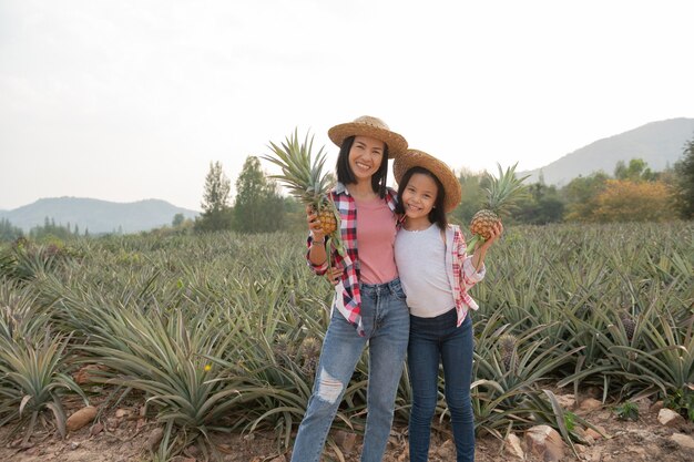 L'agricoltore femminile asiatico vede la crescita dell'ananas in fattoria, concetto di industria agricola.