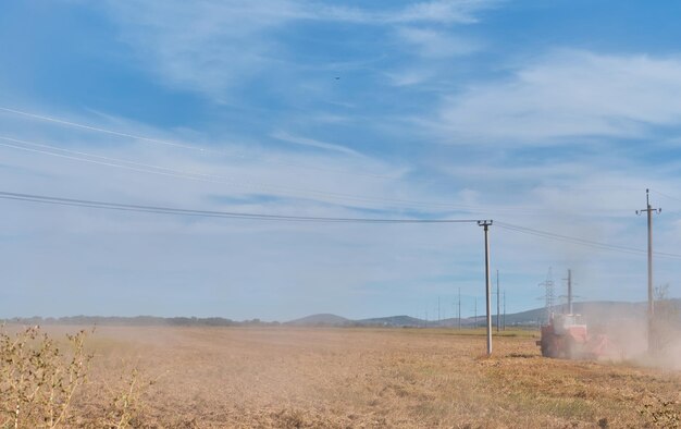 L'agricoltore su un trattore prepara il terreno con un coltivatore come parte del lavoro di pre-semina durante la stagione agricola del terreno