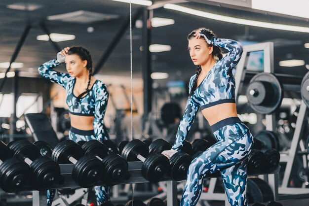 L&#39;allenamento di esercizio della donna nella rottura di forma fisica della palestra si rilassa tenendo la testa di legno