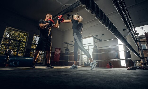 L'allenatore di boxe e il suo nuovo studente hanno uno sparring sul ring indossando guanti da boxe.