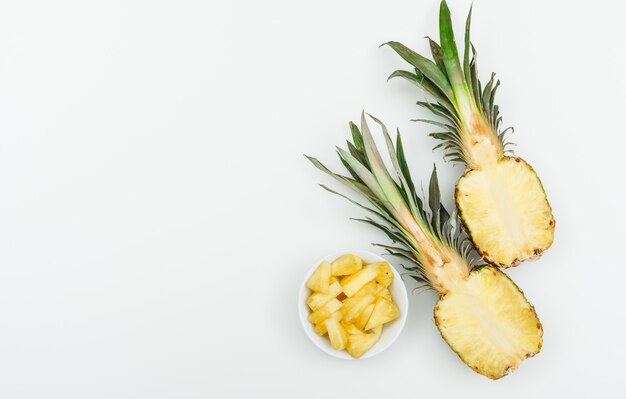 L'ananas ha tagliato a metà e fette in una ciotola bianca su un bianco. disteso.