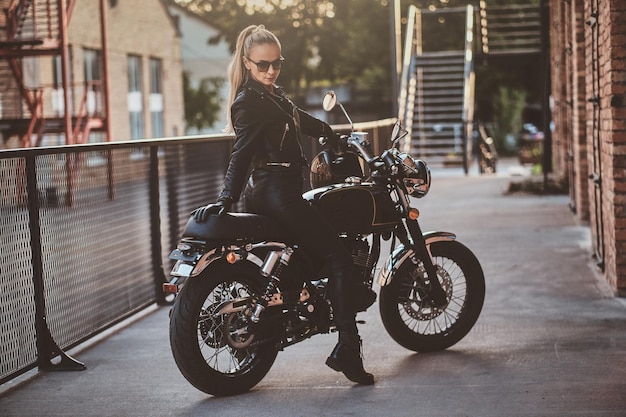 L'elegante motociclista è seduta sulla sua bici nera mentre posa per un servizio fotografico per strada.
