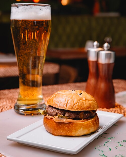 L'hamburger di manzo con salsa di cetriolo sottaceto è servito al ristorante con birra verticale