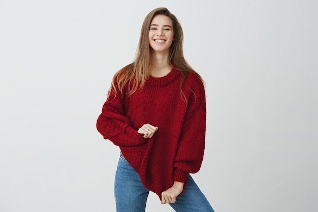 L'ho comprato in vendita. Donna spensierata emotiva in attrezzatura alla moda che sembra felice e soddisfatta mentre posando e sorridendo, allungando maglione, stando. Ho ricevuto un buon feedback