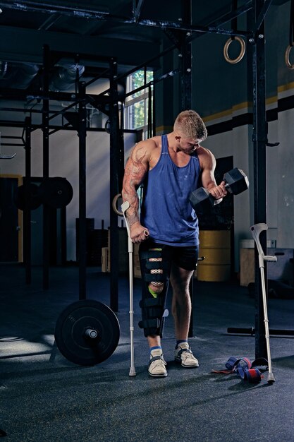 L'immagine completa del bodybuilder con le stampelle tiene il manubrio.