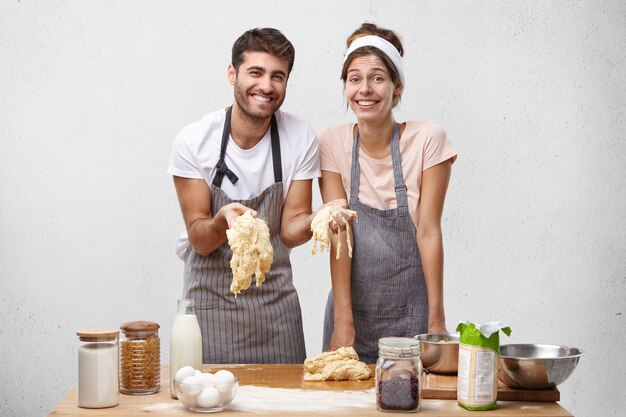 L'immagine della femmina e del maschio deliziosi felici prepara la pasta per cuocere il pane