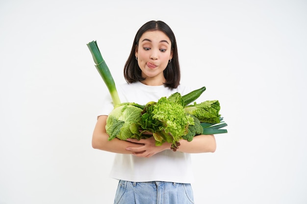 L'immagine della ragazza coreana vegetariana contiene verdure crude isolate su sfondo bianco