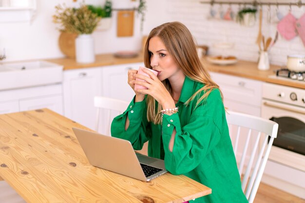 L'immagine di stile di vita indoor di una donna blogger alla moda tocca il suo laptop, il concetto di home office.