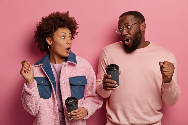 L'immagine di una giovane donna e un uomo di colore spensierato divertito ballano allegramente, bevono caffè da asporto, esprimono emozioni positive