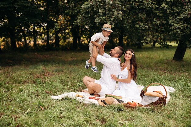 L'immagine di una giovane femmina e di un maschio caucasici allegri tiene il bambino per mano, sorride e si rallegra