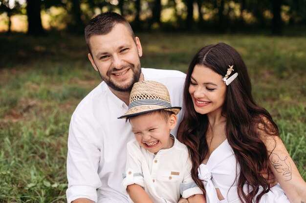 L'immagine di una giovane femmina e di un maschio caucasici allegri tiene il bambino per mano, sorride e si rallegra