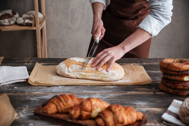 L'immagine potata del panettiere del giovane ha tagliato il pane.