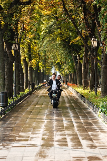 L'immagine verticale di giovani coppie eleganti guida su una motocicletta moderna