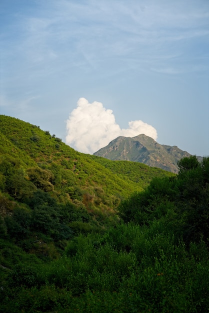 L'immagine verticale di un pittoresco paesaggio di montagna contro nuvole e cielo blu