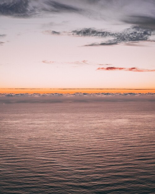 L'immagine verticale di una splendida vista sull'oceano con onde e un orizzonte arancione