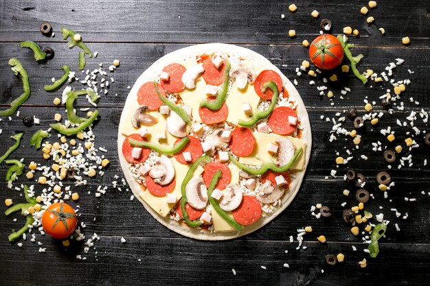 L'impasto della pizza con formaggio ai funghi peperoni in cima accanto al formaggio spruzza il pomodoro del cereale verde oliva